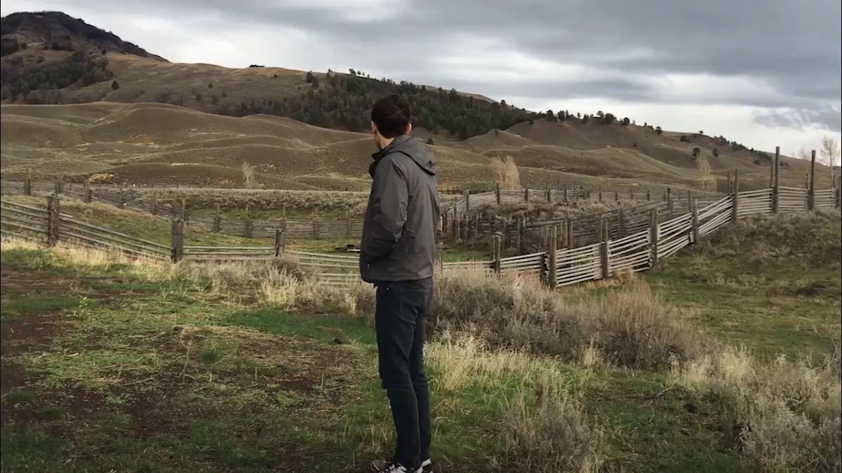 Zach walks across a brige over a roaring river